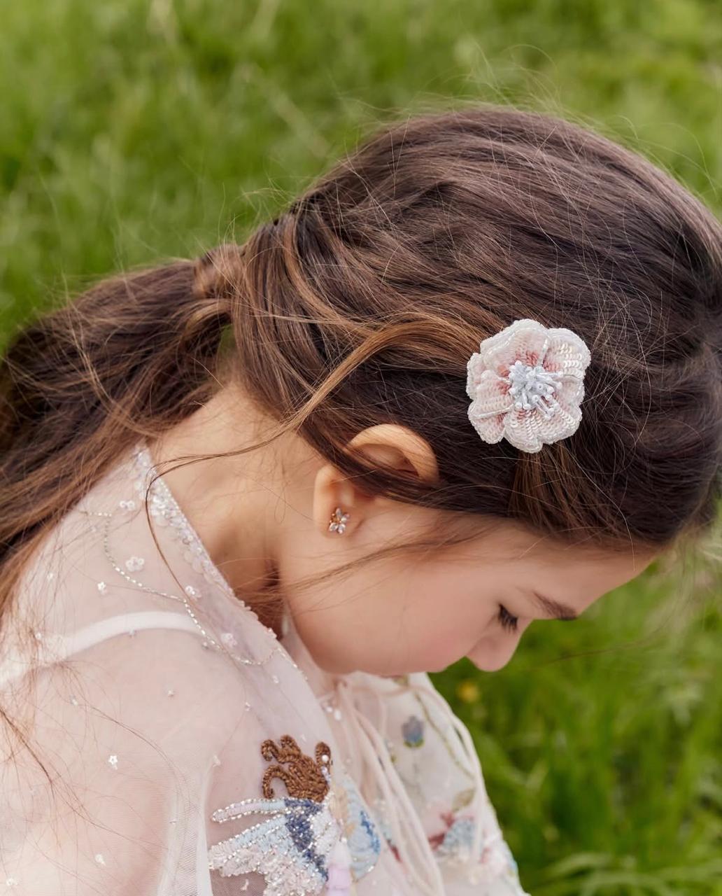 Girl wearing the Rosette Clip peach flower hair accessory by House of Carousél