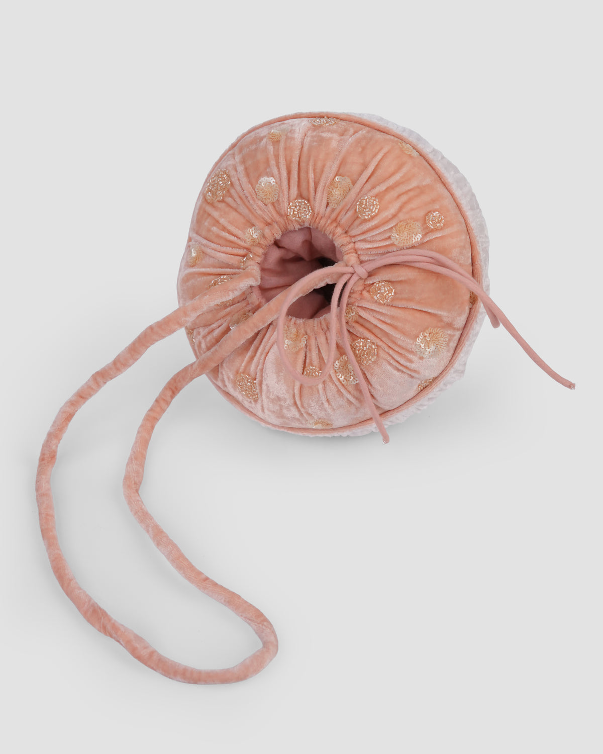 Overhead view of the Whimsy Shroom Bag with its round peach embroidered cap and long strap laid out by House of Carousél